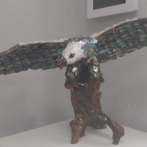An Eagle made of Abalone landing on a wooden branch