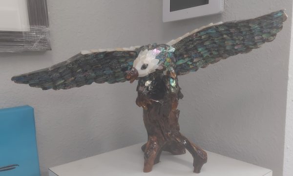 An Eagle made of Abalone landing on a wooden branch